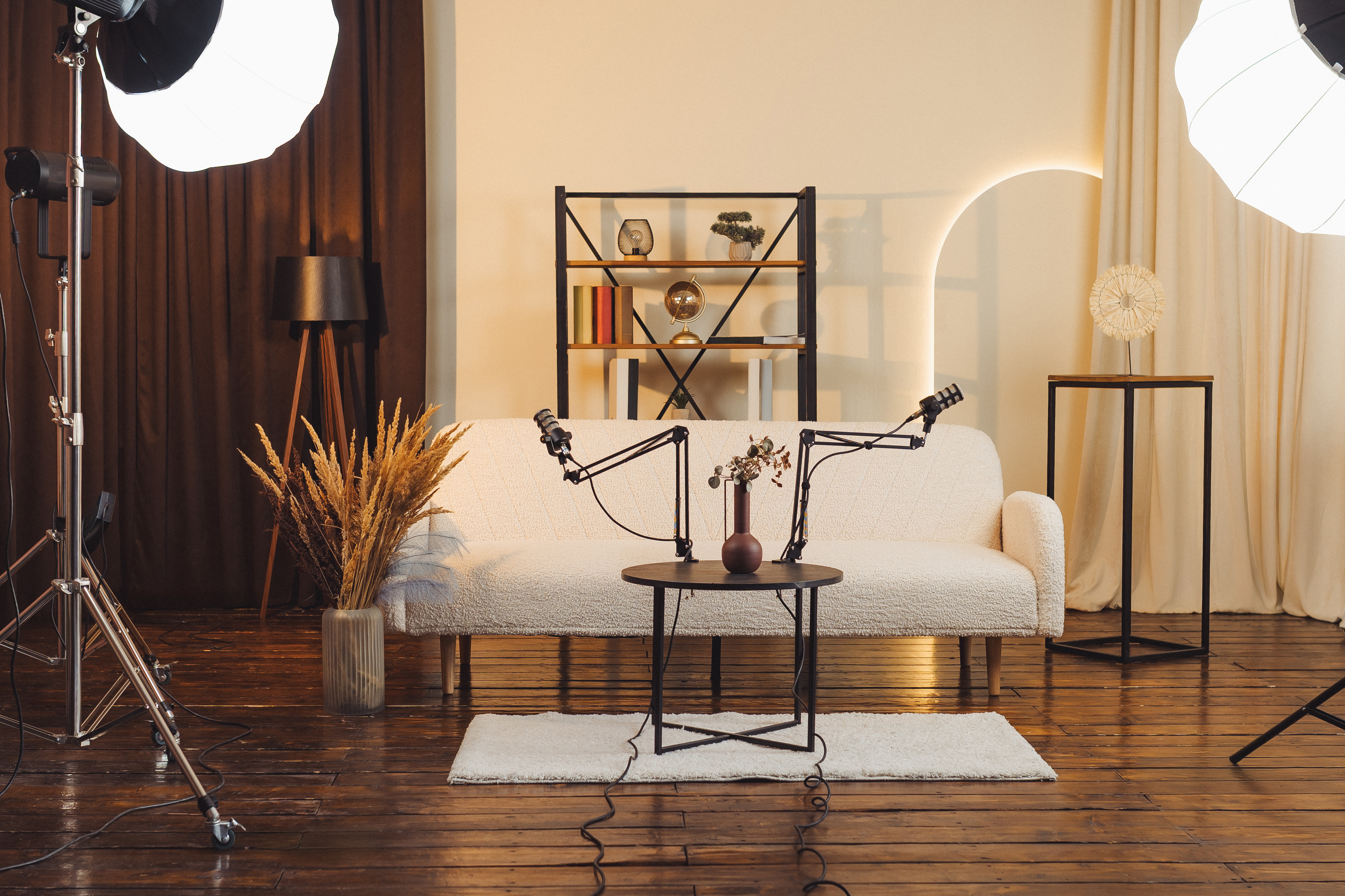Podcast studio setup with microphones on a table and decorative elements in a warm space